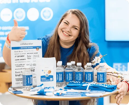 Miembro del equipo de Collaborator haciendo el gesto de «ok» junto al merchandising de marca en BrightonSEO 2026.